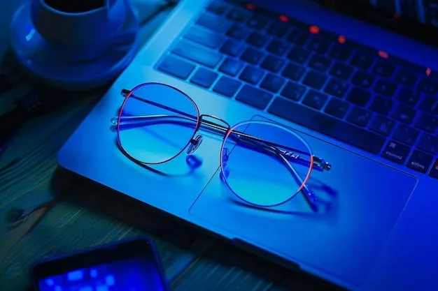 A pair of blue light blocking glasses on a wooden table, with a laptop emitting blue light in the background.