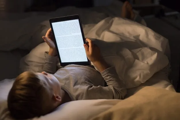 A person in bed reading a physical book, with a bedside lamp providing warm lighting, and a smartphone placed face down on the nightstand.