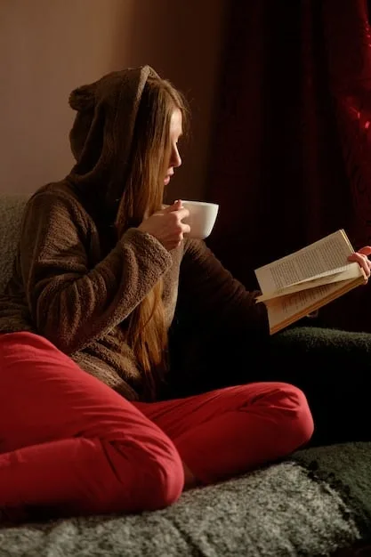A person reading a physical book in a comfortable armchair, with a warm cup of tea on a side table. Sunlight streams through the window, creating a peaceful and inviting reading nook.