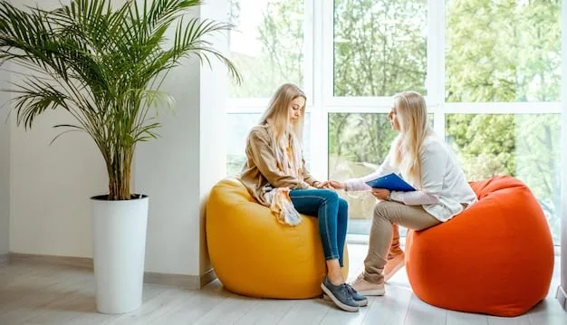 A therapist sitting across from a young adult in a brightly lit office. The therapist is listening attentively, while the young adult is looking down with a worried expression. There are pamphlets about mental health and climate change on the table between them.