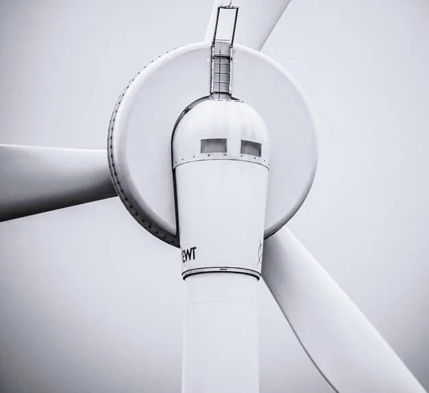 Close up shot of a wind turbine blade being manufactured in a modern factory. The focus is on the precision and technology involved in creating these renewable energy components.