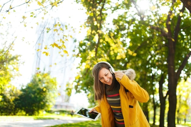 A person wearing headphones and walking through a city park on a sunny day, incorporating nature into their commute.