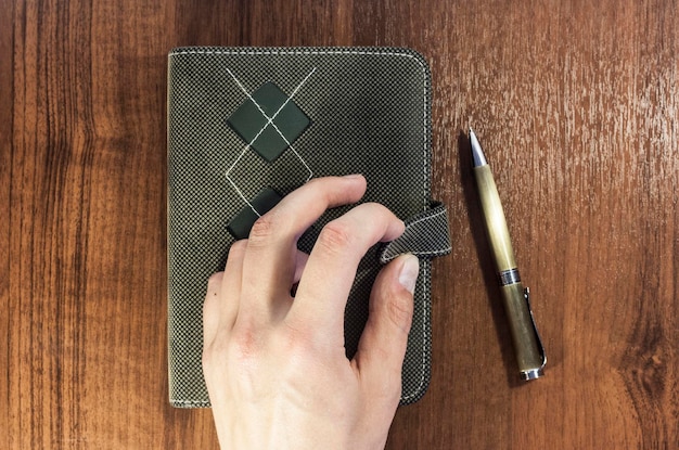 A close-up shot of a person's hands writing in a leather-bound journal, with a pen resting on the page. The background is softly blurred, with warm colors and a hint of a cozy indoor setting, emphasizing the comfort and privacy of journaling.