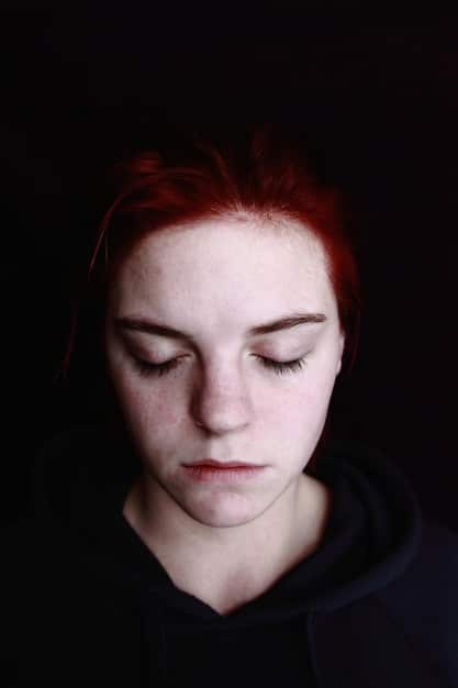 A close-up of a person's face, with a slightly downcast expression, suggesting feelings of loneliness and introspection. The lighting is soft and diffused, adding to the emotional depth of the image.