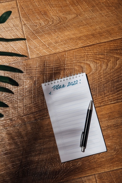A close-up shot of a notebook and pen on a wooden desk, with the words 
