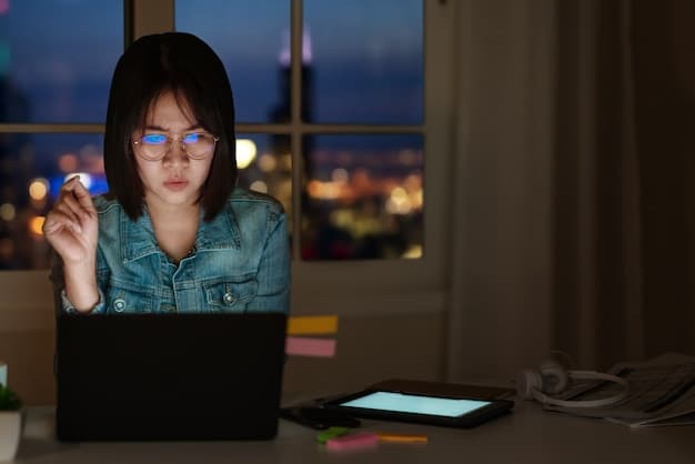 A person wearing blue light blocking glasses while working on a computer in the evening, showing the orange tint of the lenses and the reduced glare from the screen.