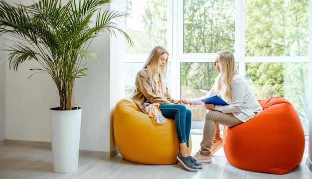 A therapist sitting across from a young adult in a brightly lit office. The therapist is listening attentively, while the young adult is looking down with a worried expression. There are pamphlets about mental health and climate change on the table between them.
