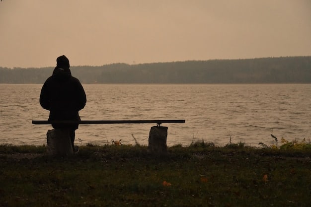 A solitary figure sitting alone on a park bench, head in hands, conveying a sense of deep loneliness and isolation. The background is blurred.