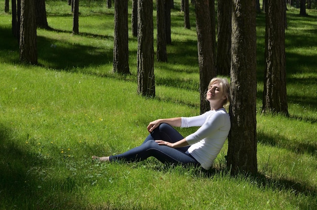 A person sitting on a park bench, eyes closed, taking a deep breath, with trees and greenery surrounding them, symbolizing a connection with nature and peaceful relaxation.