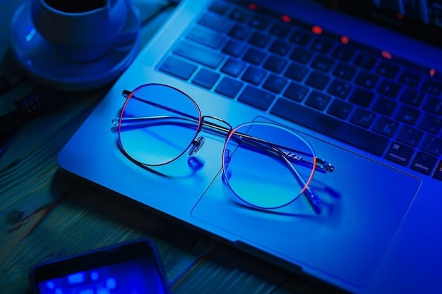 A pair of blue light blocking glasses on a wooden table, with a laptop emitting blue light in the background.