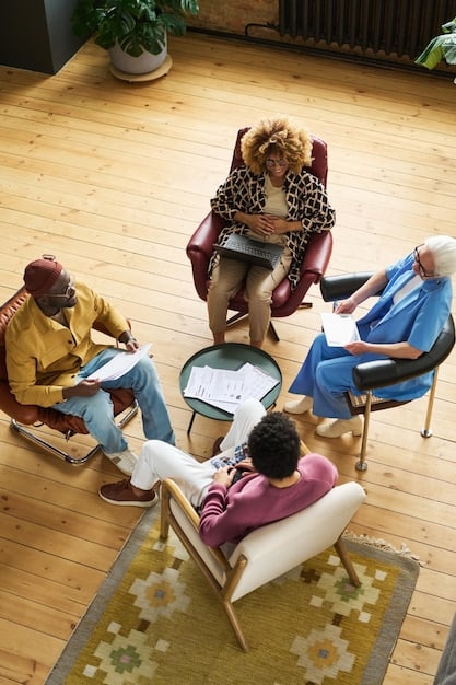 A diverse group of people sitting in a circle, participating in a group therapy session. A therapist is facilitating the discussion, and the participants appear engaged and supportive of each other. The setting is a well-lit, comfortable room.